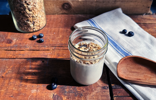 A small jar of kefir on a wooden table with blueberries